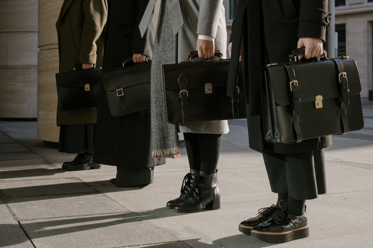 About Three professionals stand with leather briefcases, illustrating business style.