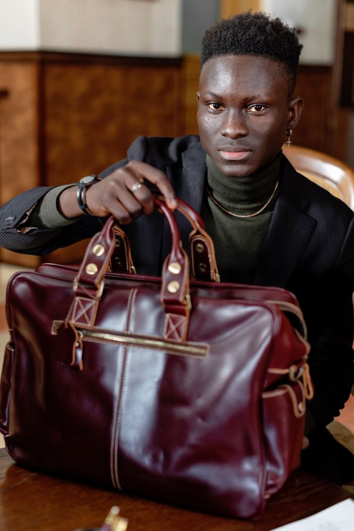 Home Confident man holding a sophisticated leather bag in an office setting.
